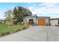 Charming single-story home with light blue exterior, orange doors, and beautiful landscaping at 840 Del Prado Dr, Kissimmee, FL 34758