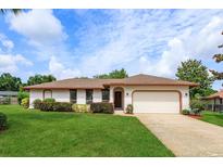 Charming single-story home with a well-maintained lawn, brick trim, and an attached two car garage at 8988 Angelica Dr, Orlando, FL 32836
