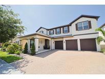Beautiful two-story home with a three-car garage, landscaped yard, and paver driveway at 9257 Outlook Rock Trl, Windermere, FL 34786