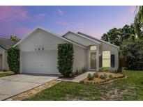 Charming single-story home featuring a two-car garage, modern landscaping, and a well-maintained lawn at sunset at 103 Gleason Cv, Sanford, FL 32773