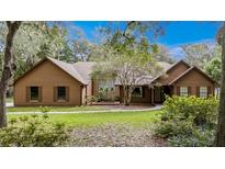 Charming home featuring a well-maintained lawn, mature trees, and a classic brown wood exterior at 137 Hickory Ridge Cir, Lake Mary, FL 32746