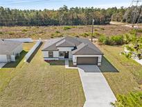 Stunning aerial view of home featuring a spacious lawn, gray roof, brown garage door, and long driveway at 16730 Sw 50Th Cir, Ocala, FL 34473