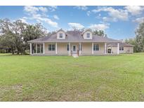Charming single-story home with a large, inviting wraparound porch and lush green lawn at 2691 Phillips Rd, Christmas, FL 32709