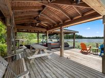 Waterfront boat dock featuring a covered area with a picnic table and an orange chair overlooking a serene lake at 2750 Lee Shore Loop, Orlando, FL 32820