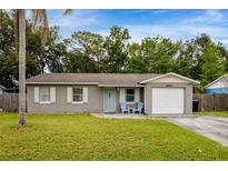 Charming single-story home featuring well-maintained landscaping, a one-car garage, and a welcoming entrance with blue chairs at 2943 Slippery Rock Ave, Orlando, FL 32826