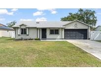 Charming one story home with a well-maintained lawn, gray exterior, and a two-car garage at 3232 Butterfield St, Deltona, FL 32738