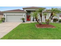 Charming single-story home featuring a red front door, palm trees, and manicured lawn at 3813 Blue Dasher Dr, Kissimmee, FL 34744