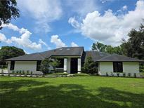 Striking single-story home featuring a modern design, lush landscaping, and a well-manicured lawn at 4454 Aspenwood Ct, Orlando, FL 32835