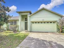 Inviting single-story home featuring an attached two-car garage and manicured lawn at 451 Acacia Tree Way, Kissimmee, FL 34758