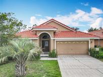Inviting single-story home with a red tile roof, palm tree, and a well-maintained lawn at 512 Viola Dr, Davenport, FL 33837