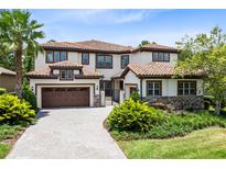 Elegant two-story home featuring a red tile roof, lush landscaping, and a paved driveway leading to a two-car garage at 8480 Adalina Pl, Orlando, FL 32827