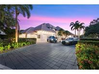 Stunning home exterior featuring a paver driveway, lush landscaping, and luxury cars at dusk at 9138 Great Heron Cir, Orlando, FL 32836