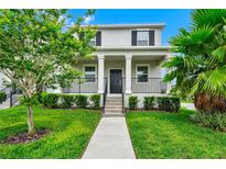 Charming two-story home with a welcoming front porch, manicured lawn, and lush landscaping at 9909 Alliteration Aly, Winter Garden, FL 34787