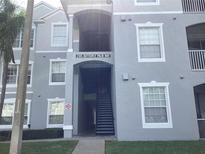 A light grey condominium building with an open walkway in a lush, green community at 2305 Butterfly Palm Way # 304, Kissimmee, FL 34747