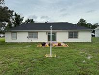An outdoor view of the home with a lush lawn and a charming patio area for relaxation at 2864 Trenton Ln, Deltona, FL 32738