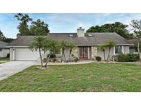 Charming single-story home features stone accents, a well-manicured lawn, and mature landscaping with palm trees at 353 Wekiva Cove Rd, Longwood, FL 32779