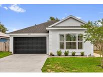 Charming single-story home with a well-manicured lawn, black garage door, and neutral paint at 3622 Huntwicke Blvd, Davenport, FL 33837