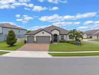 Beautiful single-story home with manicured lawn, brick driveway, and a three-car garage at 418 Gleaming Andover Way, Longwood, FL 32779