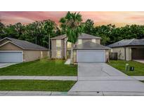 Two-story home features a well-manicured lawn, a two-car garage, and mature palm trees against a vibrant sunset backdrop at 4519 Willamette Cir, Orlando, FL 32826
