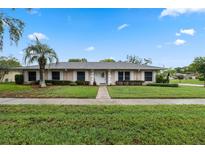 Charming single-story home featuring a well-manicured lawn and a mature palm tree in the front yard at 5089 Jennifer Pl, Orlando, FL 32807