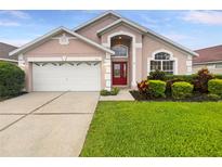 Charming single-Gathering home with red double-door entry, manicured lawn, and two car garage at 5231 Alavista Dr, Orlando, FL 32837