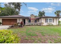 Charming single-story home featuring a well-maintained front yard and a two-car garage at 7058 Archwood Dr, Orlando, FL 32819