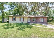 Charming single-story home featuring a well-maintained lawn and mature shade trees at 881 Cedar Cir, Tavares, FL 32778