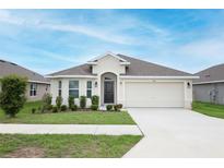 Charming single-story home featuring a two-car garage, well-maintained lawn, and inviting front entrance at 1061 Citrus Landings Blvd, Davenport, FL 33837