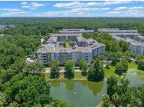 Scenic aerial view of multi-Gathering buildings surrounded by lush greenery and a tranquil pond at 1200 Ironsmith Dr # 508, Celebration, FL 34747