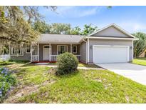 Charming gray home with a two car garage, covered porch, and well maintained front yard at 13018 S Sunset Ter, Winter Garden, FL 34787