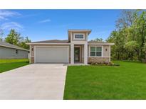 Charming single-story home featuring a well-manicured lawn, a two-car garage, and stone accents at 16357 Se 88Th Ct, Summerfield, FL 34491