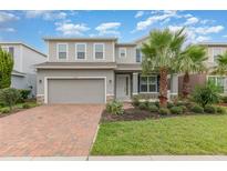 Charming two-story home featuring a brick driveway, two car garage, and manicured landscaping at 17044 Goldcrest Loop, Clermont, FL 34714
