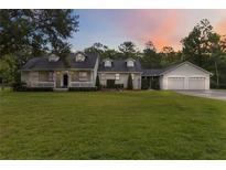 Charming home featuring a lush front lawn, inviting porch, and a three-car garage at 23647 Seneca Ridge Ct, Christmas, FL 32709