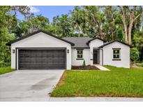 Charming single-story home boasts a black two-car garage, manicured lawn, and a welcoming entrance at 300 Cherokee Ave, Orange City, FL 32763