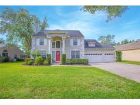Charming two-story home features a manicured lawn, three-car garage and a welcoming red front door at 3231 Furlong Way, Gotha, FL 34734