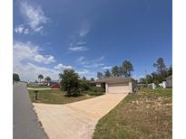 Single-story home featuring an attached two-car garage, manicured lawn, and a long driveway at 3381 Sw 129Th Loop, Ocala, FL 34473