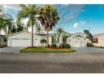 Charming single-story home with a well-manicured lawn, mature palm trees, and an attached two-car garage at 50989 Highway 27 # 176177, Davenport, FL 33897