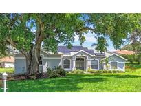 Charming single-Gathering home featuring lush landscaping, a manicured lawn, and solar panels on the roof at 5311 Saddleback Ct, Lady Lake, FL 32159