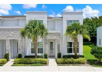 Contemporary townhome featuring a sleek white facade, stone accents, and lush landscaping at 17441 Hidden Forest Dr, Clermont, FL 34714