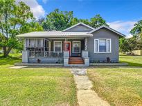 Charming single-story home featuring a cozy screened-in porch and a vibrant red front door at 1826 W Silver Springs Blvd, Ocala, FL 34475