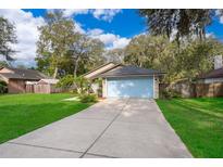 Charming single-story home with a light blue garage door and lush green lawn at 39939 Parkinsonia St, Lady Lake, FL 32159