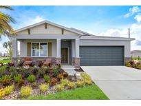 Charming single-story home with a well-manicured lawn and a gray two-car garage at 427 Shoreview Sands Ave, Mascotte, FL 34753
