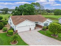 Charming home with a two-car garage, brick-lined driveway, lush landscaping, and a manicured lawn at 4830 Summerbridge Cir, Leesburg, FL 34748