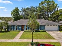 Charming blue home featuring a two-car garage, mature trees, and a lush green lawn at 1921 Geronimo Trl, Maitland, FL 32751