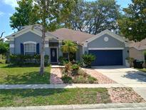 Charming single-story home with blue exterior, landscaped yard, and brick walkway at 2474 Cimmaron Ash Way, Apopka, FL 32703
