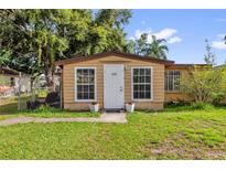 Tan home featuring a bright white door and matching window trim, complemented by potted flowers at 4133 Cepeda St, Orlando, FL 32811