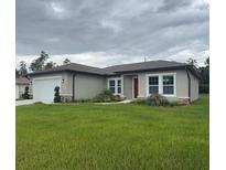 Charming single-story home with a well-manicured lawn, neutral paint, brick accents and a red front door at 524 Marion Oaks Blvd, Ocala, FL 34473