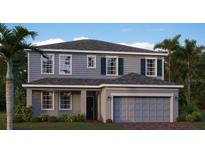 Charming two-story home featuring a gray exterior, well-maintained landscaping, and a two-car garage at 769 Tundra Loop, Groveland, FL 34736