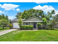 Charming one-story home with lush green lawn, mature landscaping, and a white garage door at 1210 Quintuplet Dr, Casselberry, FL 32707