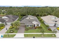 Stunning aerial view of a well-maintained home showcasing lush landscaping, a stone facade, and a tile roof in a vibrant community at 1265 Estancia Woods Loop, Windermere, FL 34786